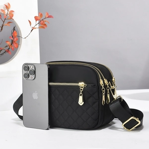 Macro view of black quilted crossbody bag with three golden zippers and wide strap