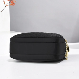 Close-up of black quilted nylon bag with three gold zippers and multi-layer storage detail