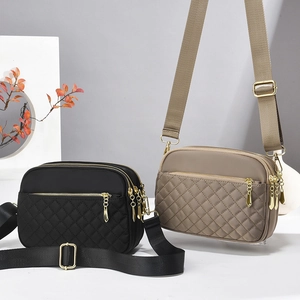 Detail of trendy crossbody bag with quilted texture, wide strap and golden hardware