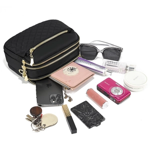 Detailed view of black quilted crossbody bag with triple zippers and storage capacity