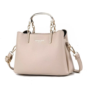 Detailed view of beige pebble grain leather handbag with gold chain handle and strap
