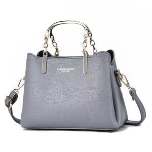 Detail of grey pebbled leather handbag with gold metal hardware and brand lettering