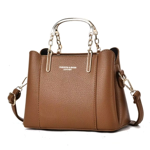 Detail of lychee pattern brown leather bag with golden arc handle and brand logo