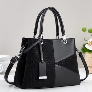 Detail of black tote bag featuring textured weaving and silver-tone metal hardware