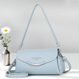 Detail of light blue crossbody bag with lychee grain texture and silver hardware logo