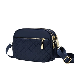 Navy blue quilted crossbody bag with three zipper compartments and adjustable strap