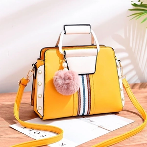 Detailed view of two-tone contrast tote bag with pearl rivets and fluffy pink charm