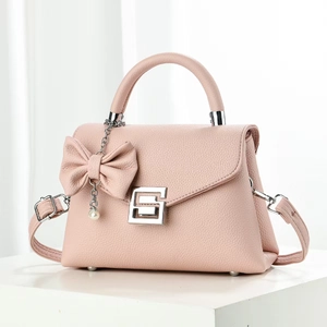 Hellrosa Lederhandtasche mit G-Schnalle und Perlen-Schleifen-Anhänger auf weißem Ständer