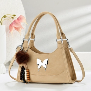Détail du sac à main en cuir kaki avec breloque papillon argentée et pompon perlé coloré