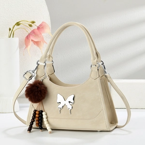 Détail du sac crème avec papillon argenté et breloque peluche dans un cadre élégant