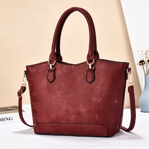Deep red tote bag in matte leather texture with gold hardware and shoulder strap details