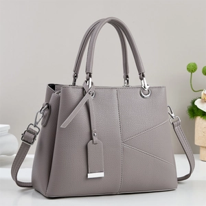 Close-up of gray pebble leather tote with asymmetric geometric stitching and silver hardware