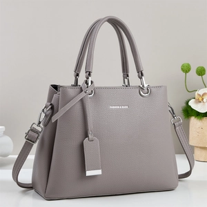 Close-up of dark grey litchi grain leather texture and metallic strap hooks on the handbag