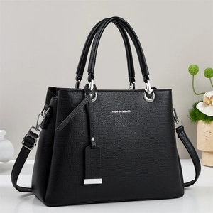 Close-up of black lychee grain texture and silver hardware on elegant tote bag
