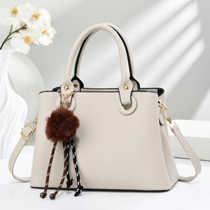 Detail of cream herringbone faux leather bag with gold rings and brown pompom charm