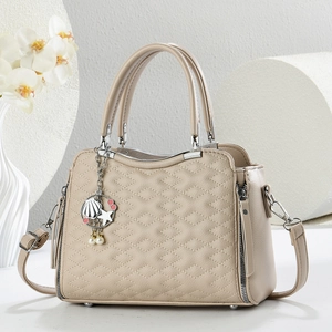 Dettaglio borsa trapuntata beige con ciondolo a stella marina e zip in metallo argento