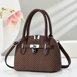 Detail of herringbone fabric handbag with dark brown leather straps and silver buckle