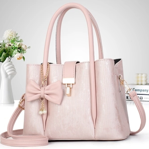 Détail du sac à main rayé rose avec breloque nœud en cuir et fermoir en métal doré