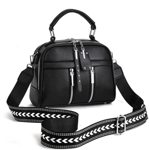 Detail of black pebbled leather handbag with wide woven geometric patterned shoulder strap