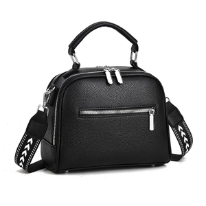 Detail of black lychee leather handbag featuring silver zippers and patterned wide strap