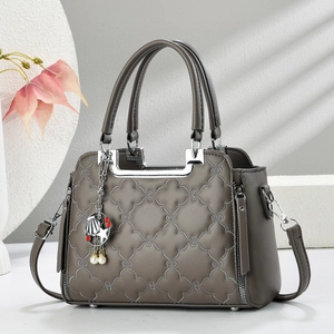 Taupe quilted tote bag with metal handle and floral texture on a minimalist background