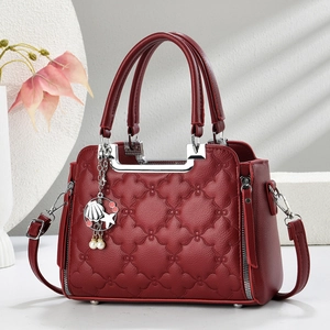 Macro shot of dark red quilted leather bag with floral stitching and metal charms