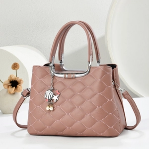 Detail of dusty rose quilted handbag with silver hardware and marine themed charms
