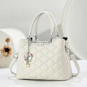 Detail of white quilted handbag with silver U-shaped metal handle and pearl charm