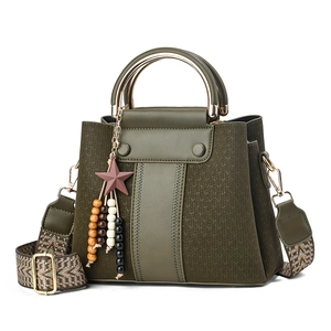 Dark green bucket bag with ethnic strap and beaded star charm on a white background