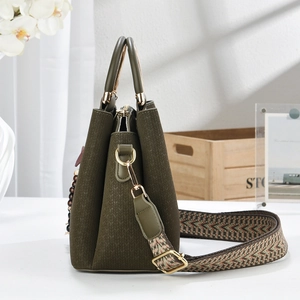 Detail of olive green woven handbag with gold circular handle and ethnic shoulder strap