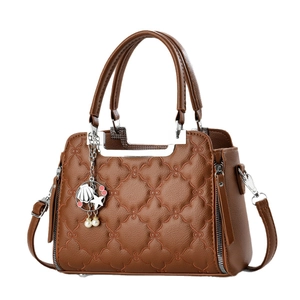 Brown leather tote bag with floral embroidery and star pendant on a white background