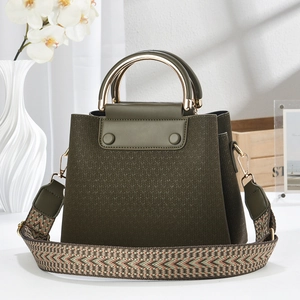 Detail of dark green woven tote bag with golden metal handle and patterned strap