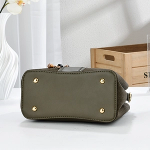 Close-up of olive green handbag base with four golden metal feet and woven leather texture