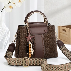 Detail view of brown textured leather bag with star charm and geometric woven strap