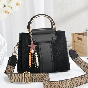 Detail of black textured handbag with golden ring handle and jacquard strap