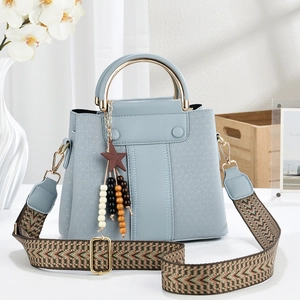 Detail of light blue faux leather handbag with gold handle and woven shoulder strap