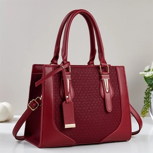 Detail of burgundy faux leather handbag with woven texture and gold hardware accents