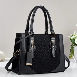 Detail of black woven texture and smooth leather handle with gold hardware on handbag