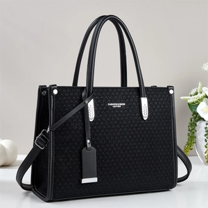 Detail of black leather tote bag with woven texture and silver-toned fashion hardware