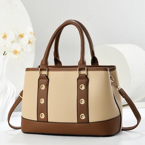 Detail of beige and brown lychee grain faux leather handbag with gold metal rings