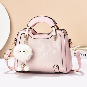 Sac à main en cuir rose avec détails dorés et pendentif monstre en peluche blanc