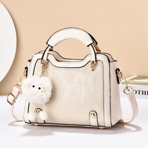 Détail du sac à main blanc crème avec textures verticales et charmant porte-clés