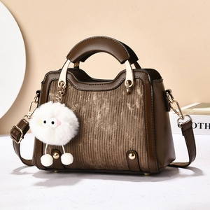 Détail du sac à main en cuir avec ferrures dorées et un porte-clés monstre en peluche blanc