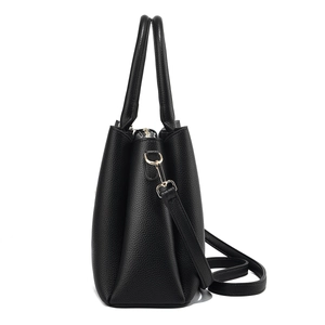 Détail du sac à main noir en cuir grainé avec fermeture dorée et bandoulière amovible