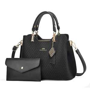 Detailed view of black textured tote bag and matching clutch with gold hardware