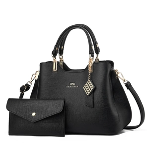 Close-up of black litchi leather handbag set with gold hardware and logo detail