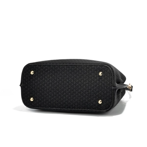 Detail view of the black textured fabric handbag base with four golden metal protective feet