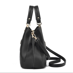 Side view of black lychee grain leather handbag with gold hardware and shoulder strap
