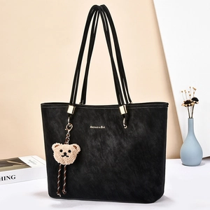Minimalist black tote bag with plush bear charm and gold hardware for office commuting