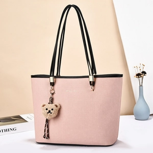 Pink minimalist tote bag with thin black straps and a plush bear charm for daily commute
